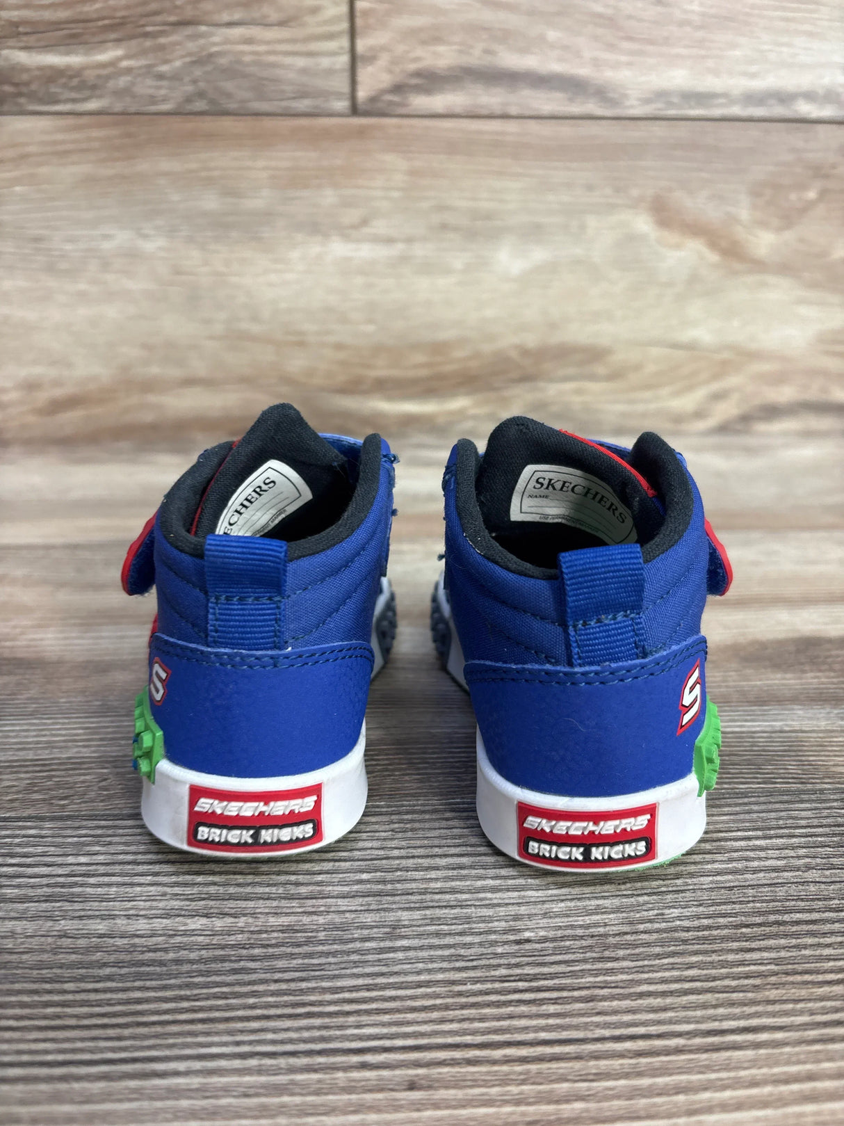 Back view of Skechers Kool Brick Lil Constructer Sneakers sz 5c in blue showcasing red Brick Kicks logo patch and green brick midsole detail on wood plank background