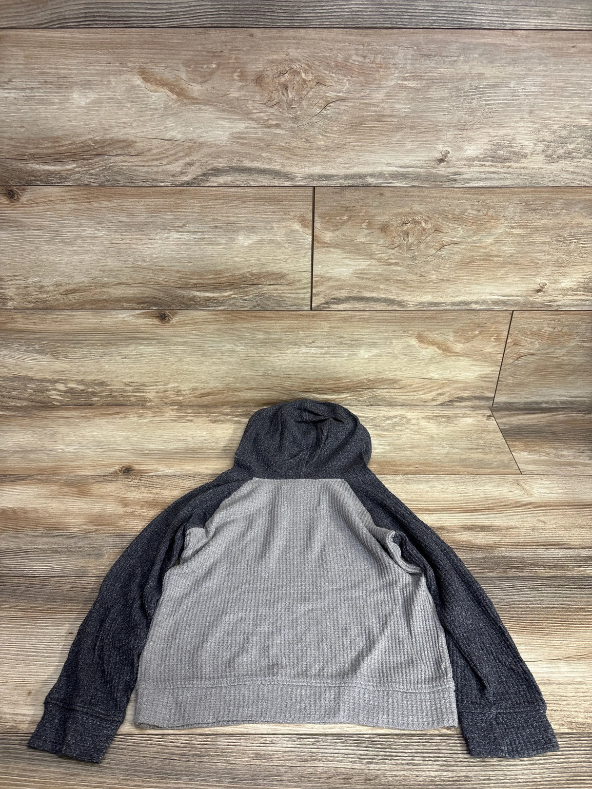 Flat lay of 5T Old Navy hooded waffle knit shirt showing gray body, dark charcoal sleeves and hood on wood floor background