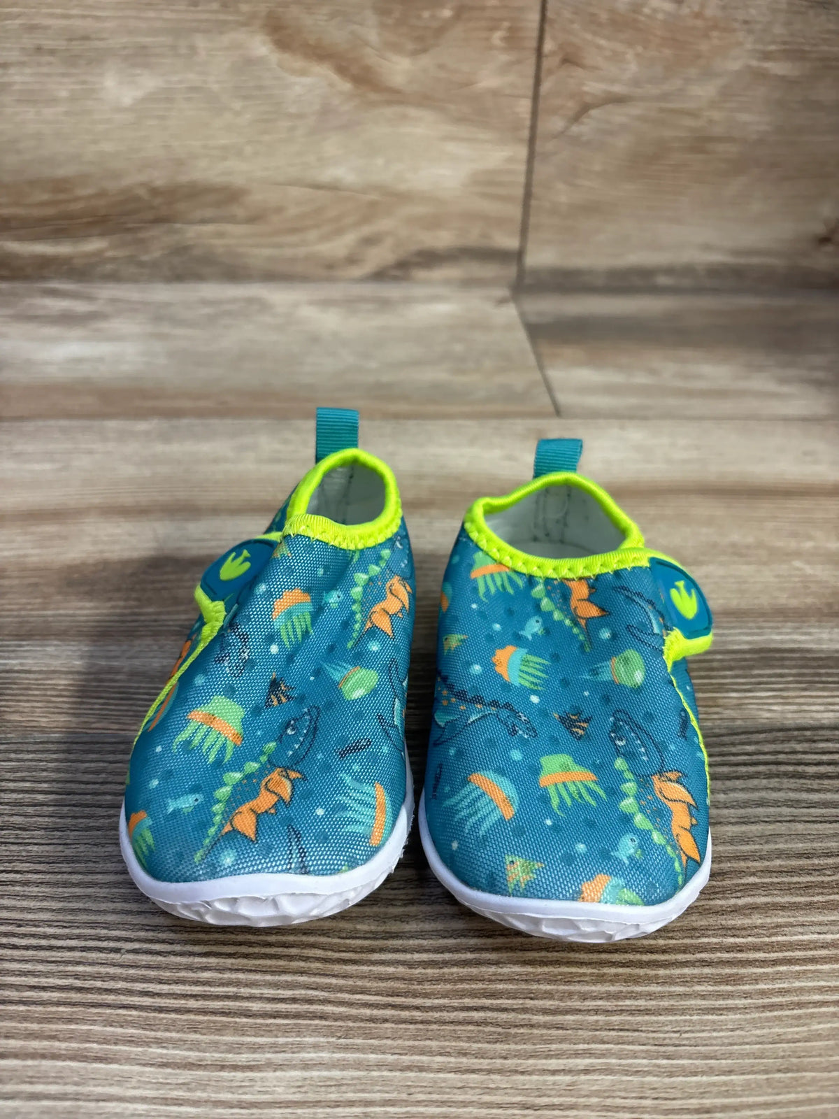 Front view of FEETCITY teal wide barefoot water shoes, size 4/5C, showcasing colorful print and white flexible soles on a wood surface