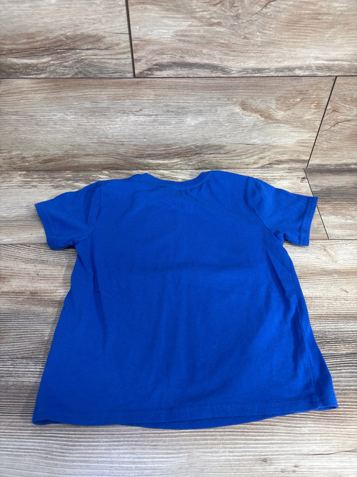 Back view of Marvel Spider-Man toddler shirt size 4-5T showing solid royal blue back, short sleeves, and crew neckline on wood floor