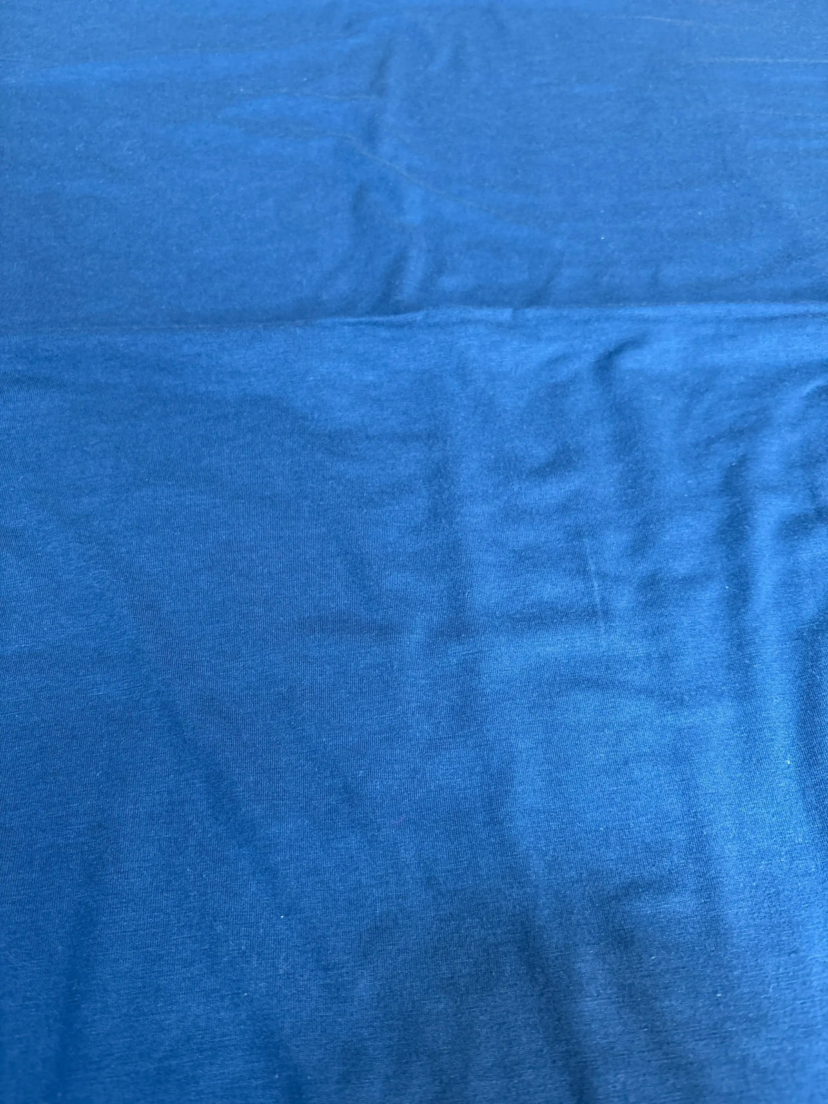 Flat lay of Copper Pearl Robin knit swaddle blanket showcasing solid robin blue knit texture and slight wrinkles