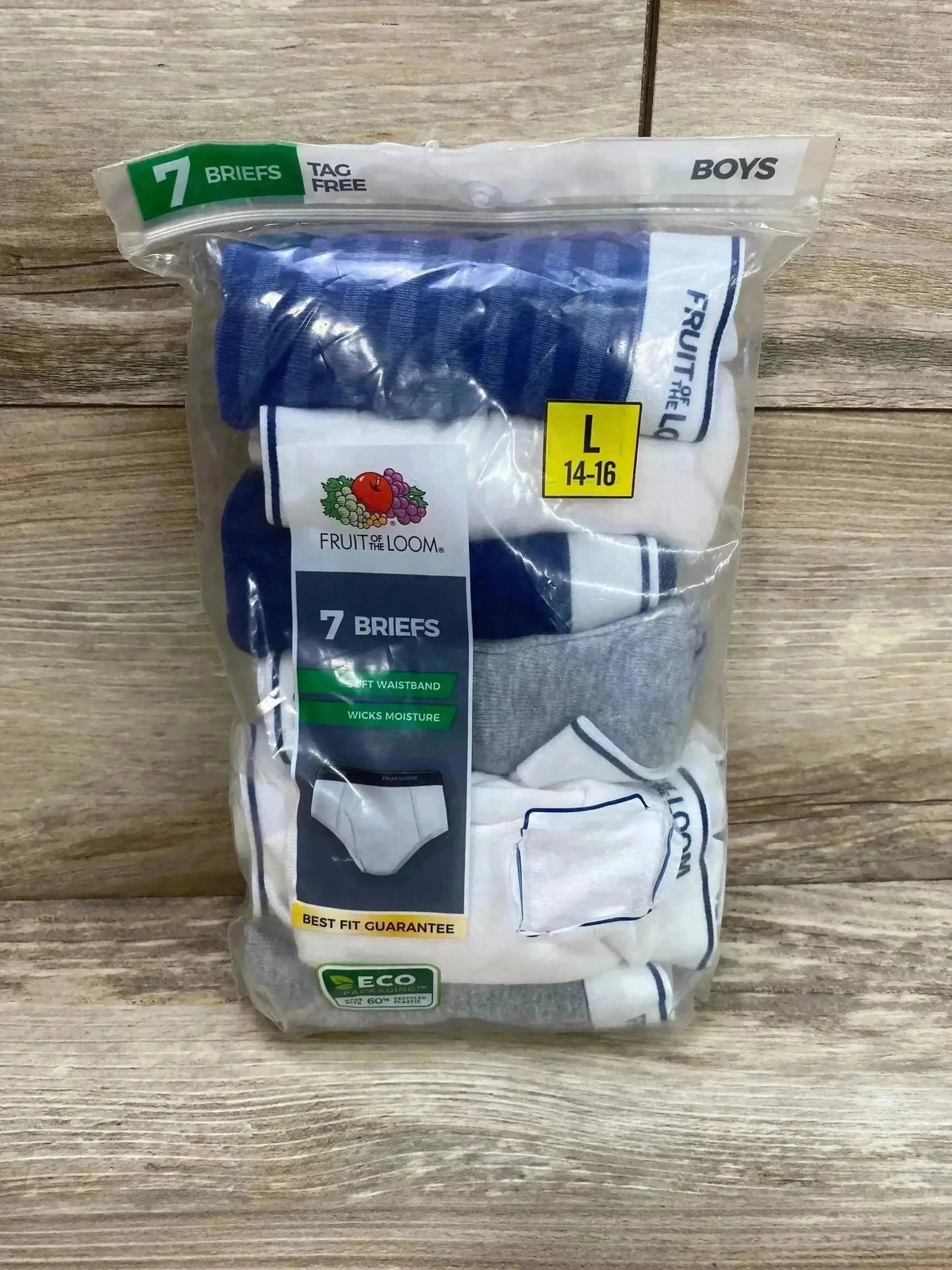 Front view of Fruit of the Loom boys’ 7-pack briefs showcasing size L (14-16), navy, white, and gray colors in sealed plastic bag on wood background
