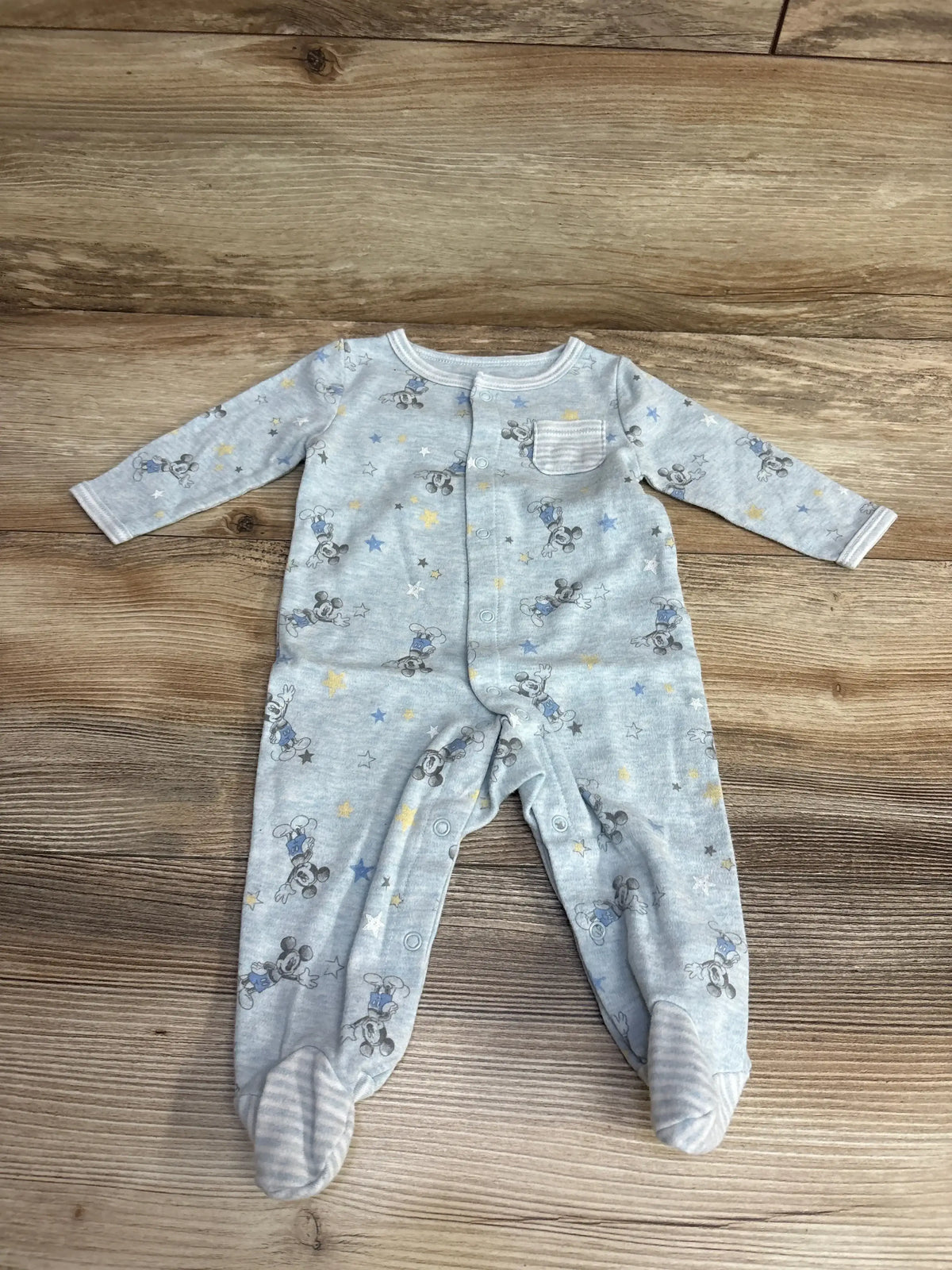 Light blue baby sleeper with cartoon mouse print, footed, long sleeves, laid on wood floor