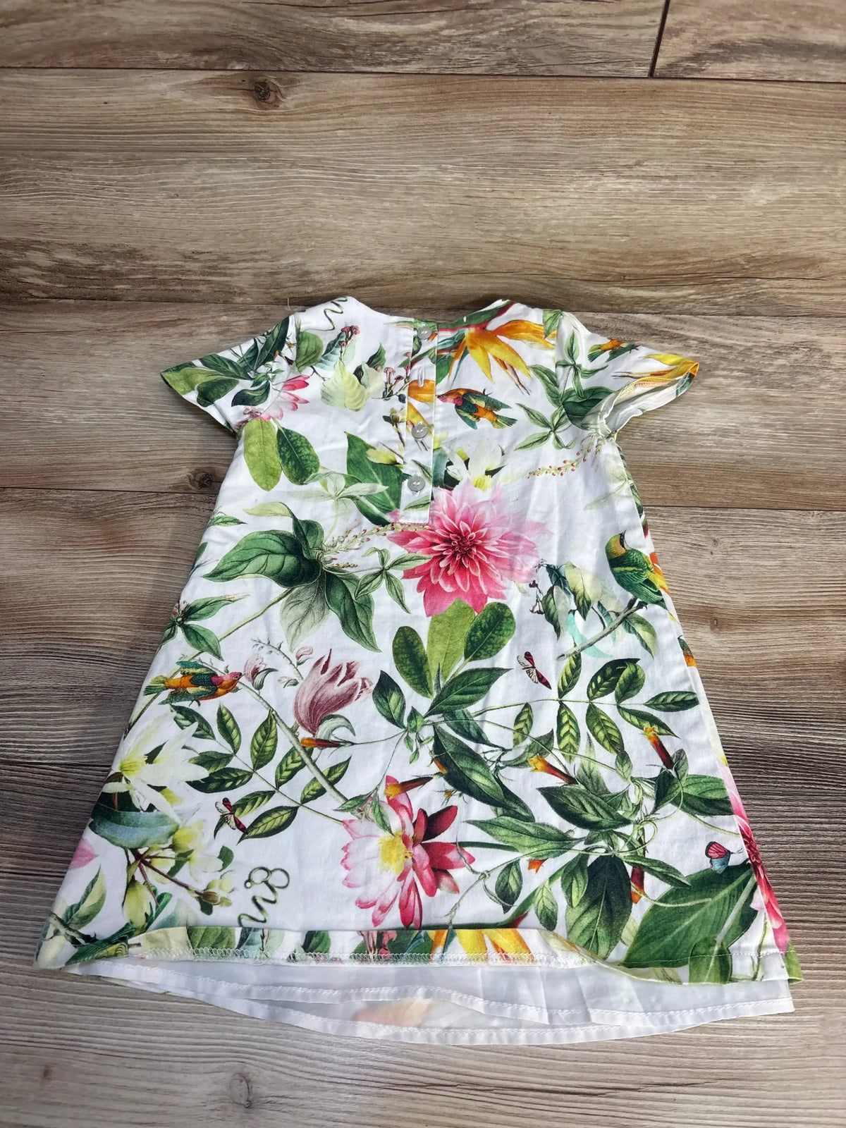 Floral short sleeve toddler dress with colorful flowers on a wooden floor