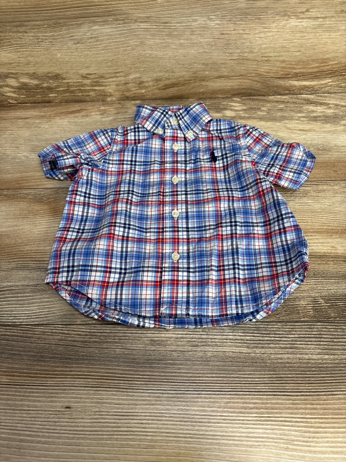 Front of toddler Ralph Lauren short blue and red plaid button shirt with button collar and navy logo on wood surface