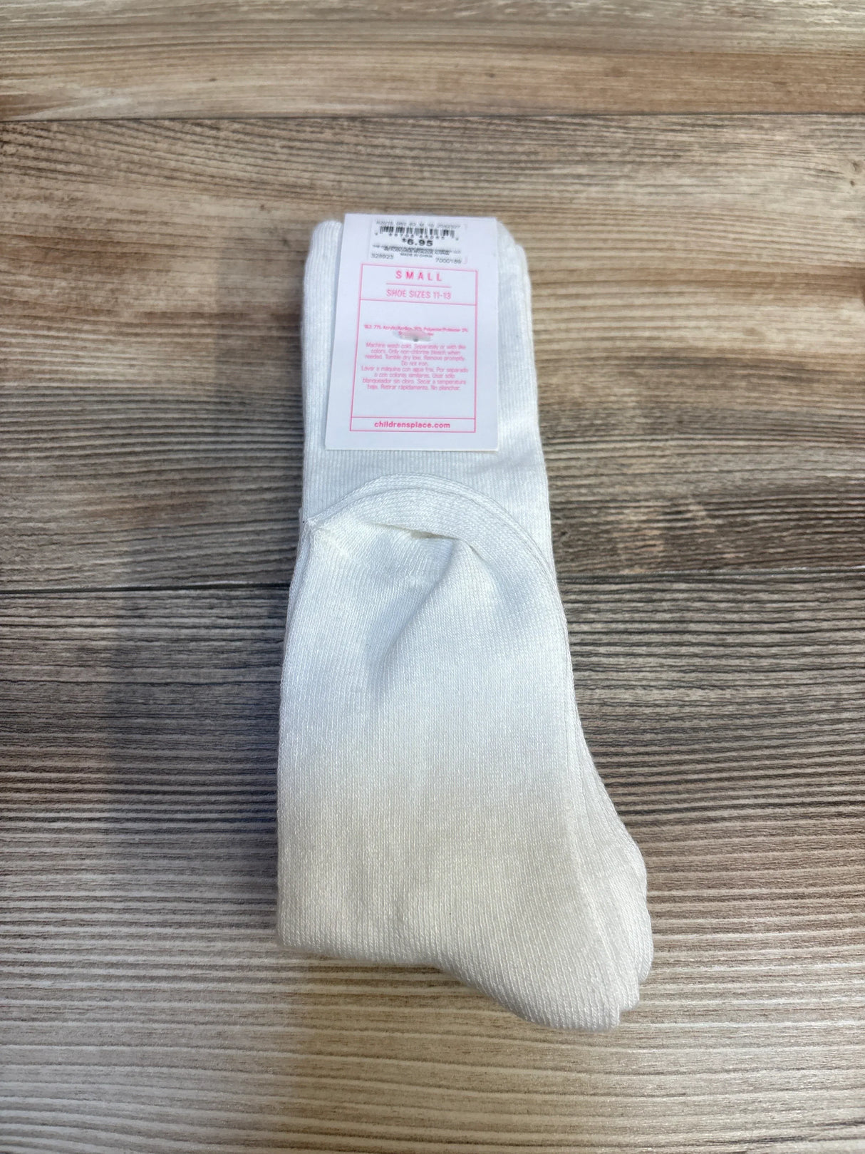 Pair of white kids socks size small on wood background