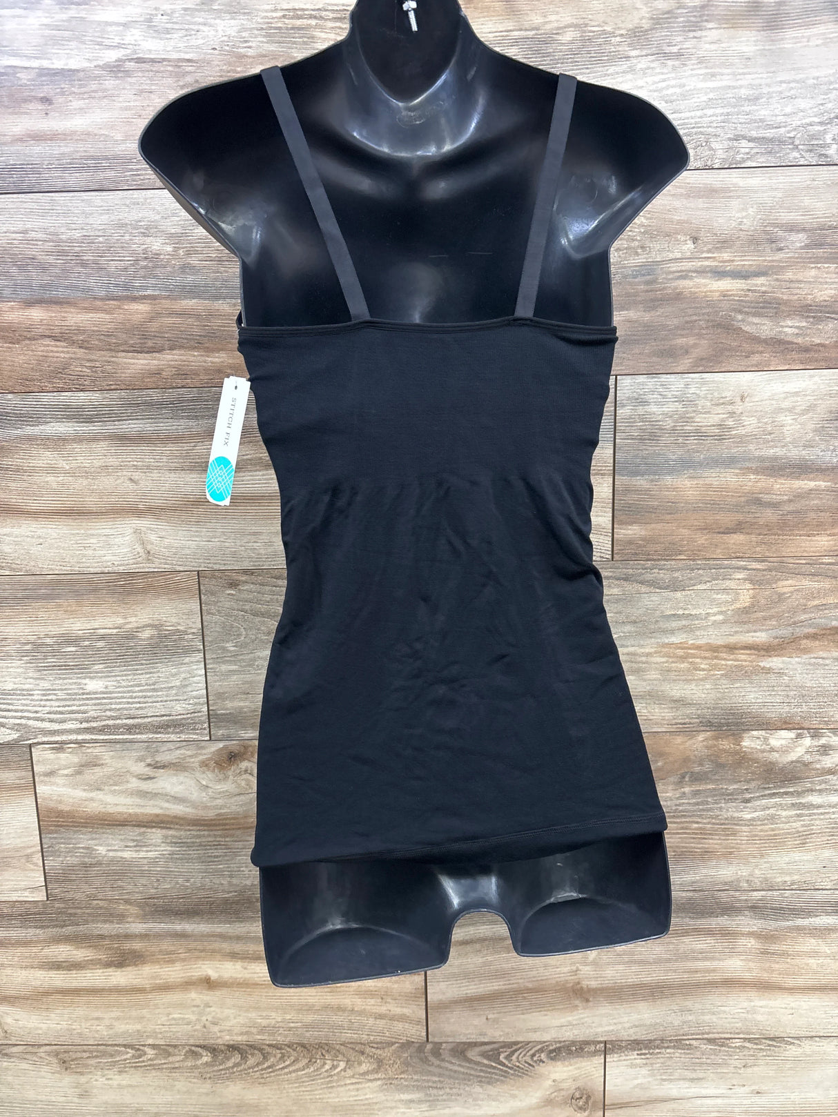 Black women's camisole top on mannequin with tag on wood floor background