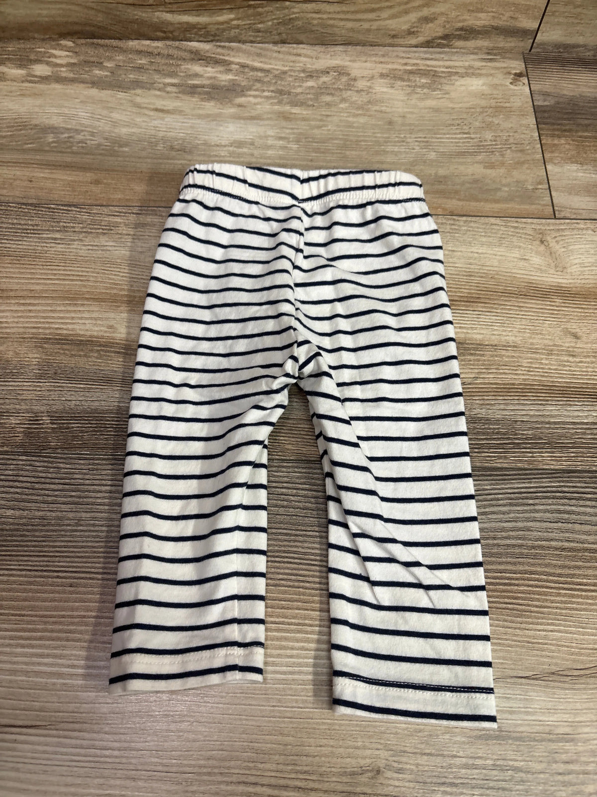 White and navy blue horizontal striped baby leggings laid flat on a wooden surface.