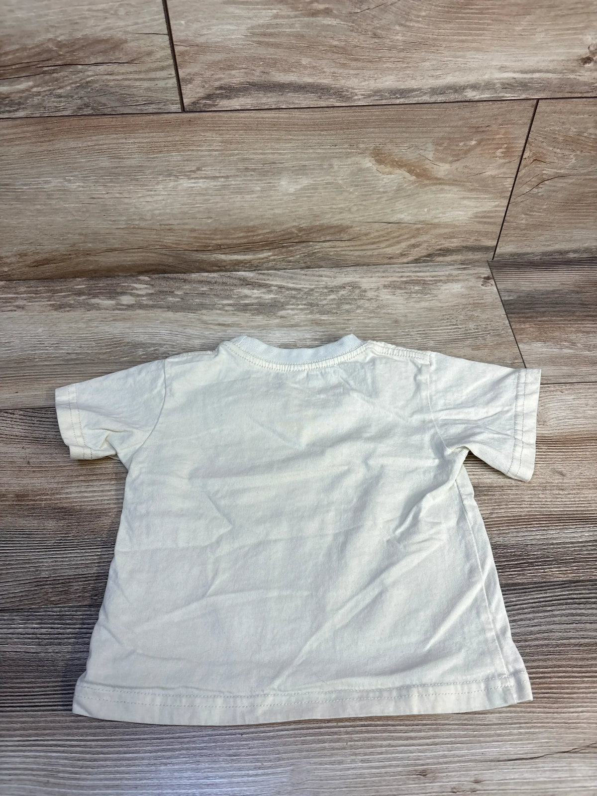 Back view of cream Cheerilulu Birthday Boy toddler tee showing short sleeves and crewneck on wood plank floor