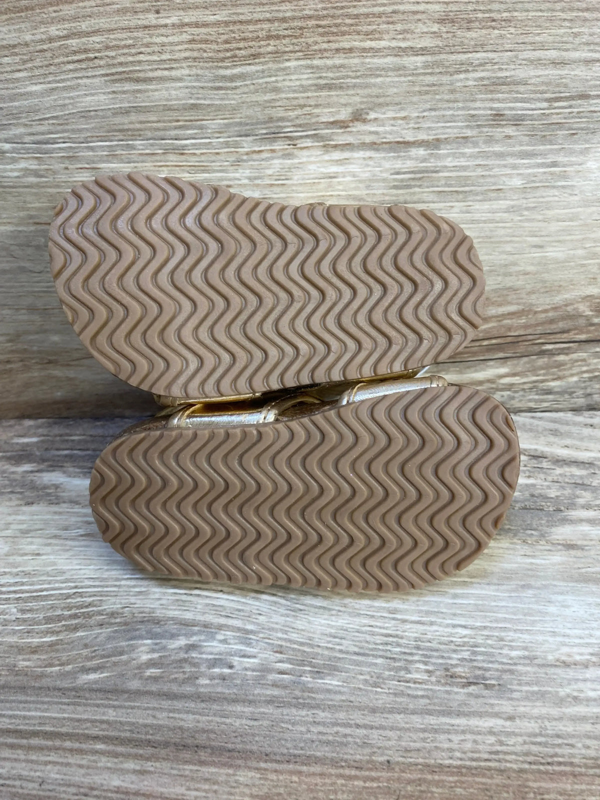 Bottom view of toddler shoes with non-slip rubber soles on wood background