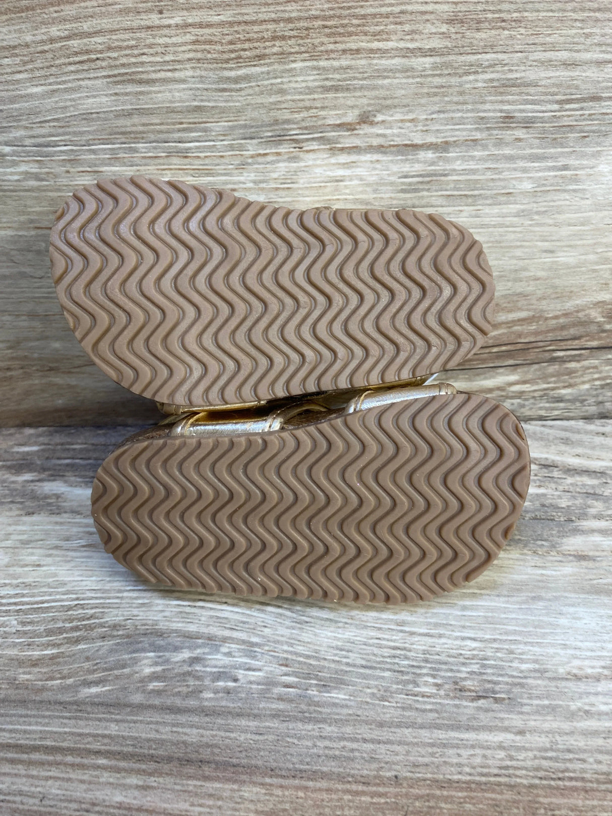 Bottom view of toddler shoes with non-slip rubber soles on wood background