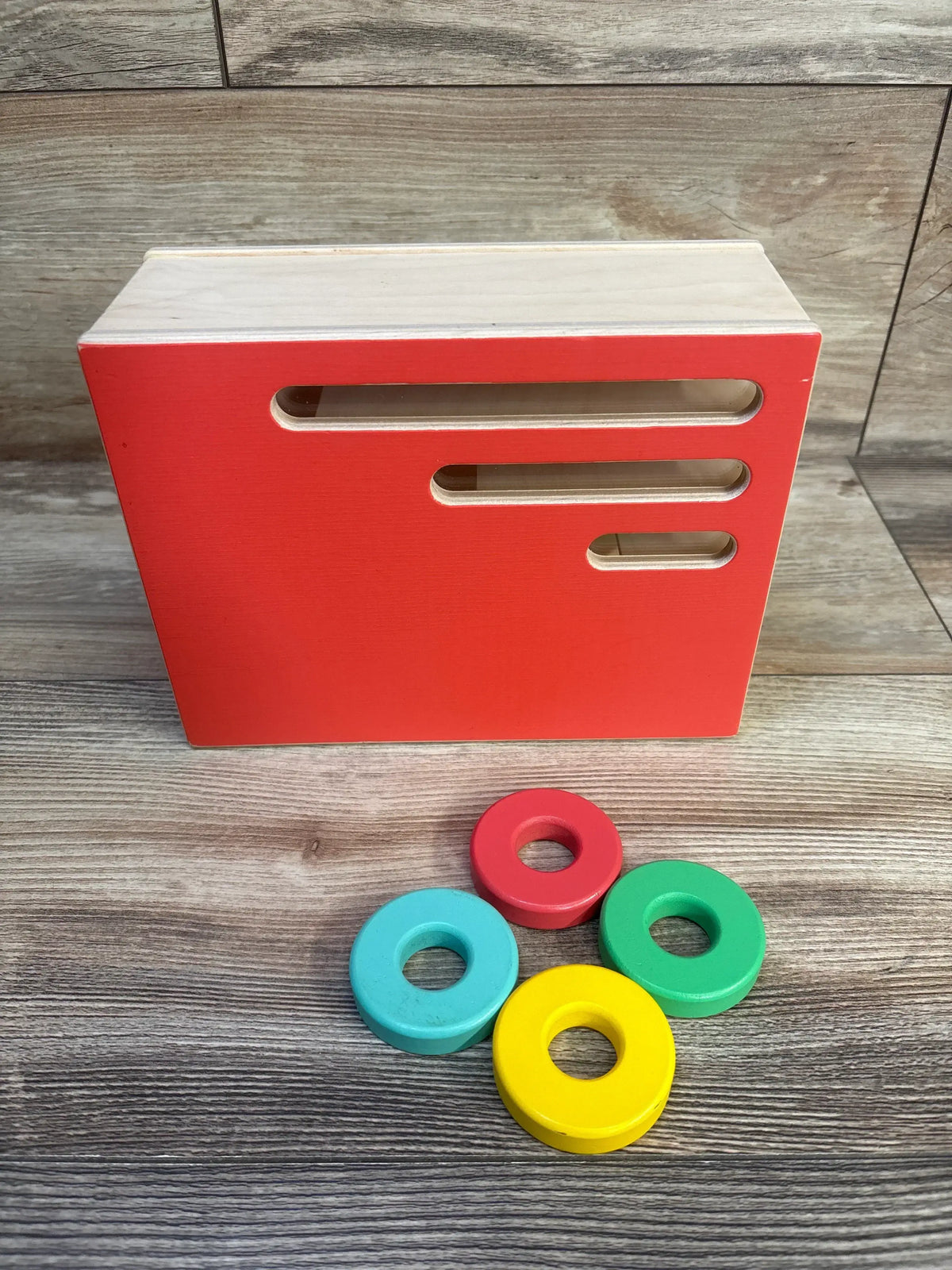 Red wooden shape sorter toy with colorful rings for toddler learning and development
