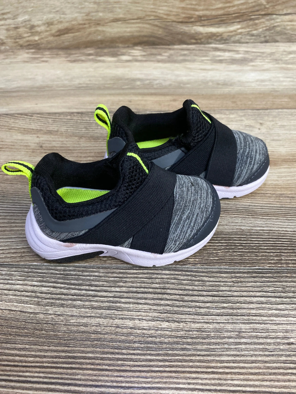 Pair of toddler slip-on sneakers with black, gray, and neon yellow design on wood surface