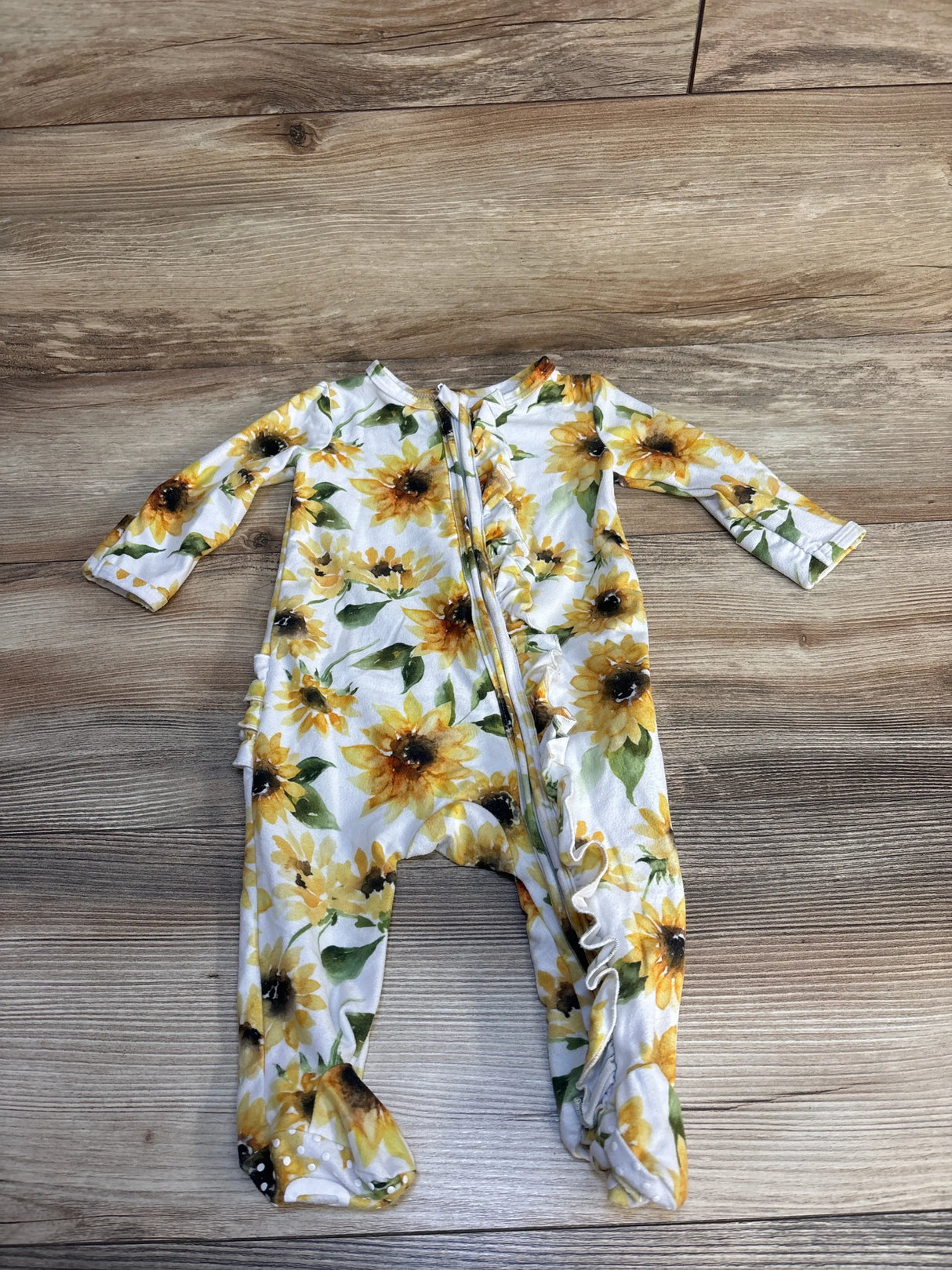 Yellow sunflower print baby sleeper with zipper on wooden floor