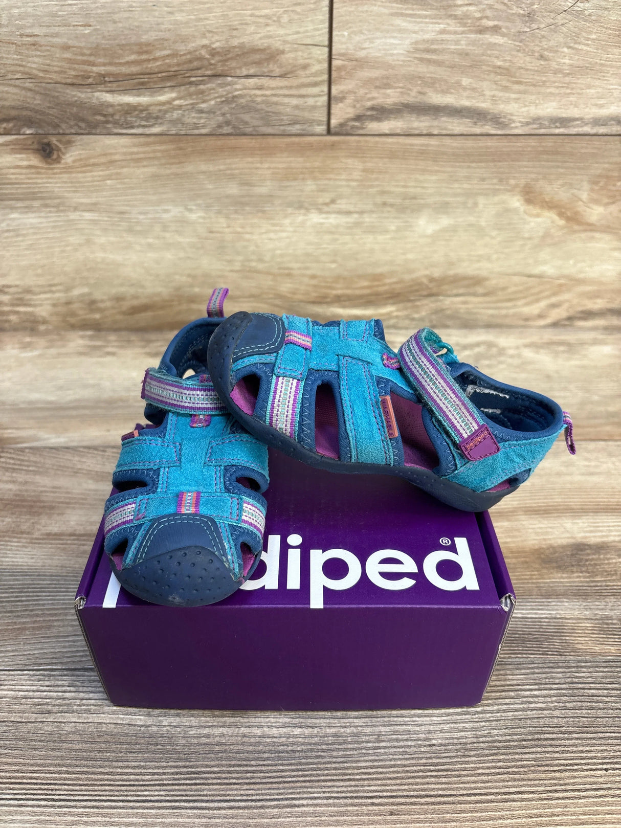 Three-quarter view of Pediped Flex Sahara kids’ sandals in blue purple on purple shoebox showing Velcro straps and rubber toe