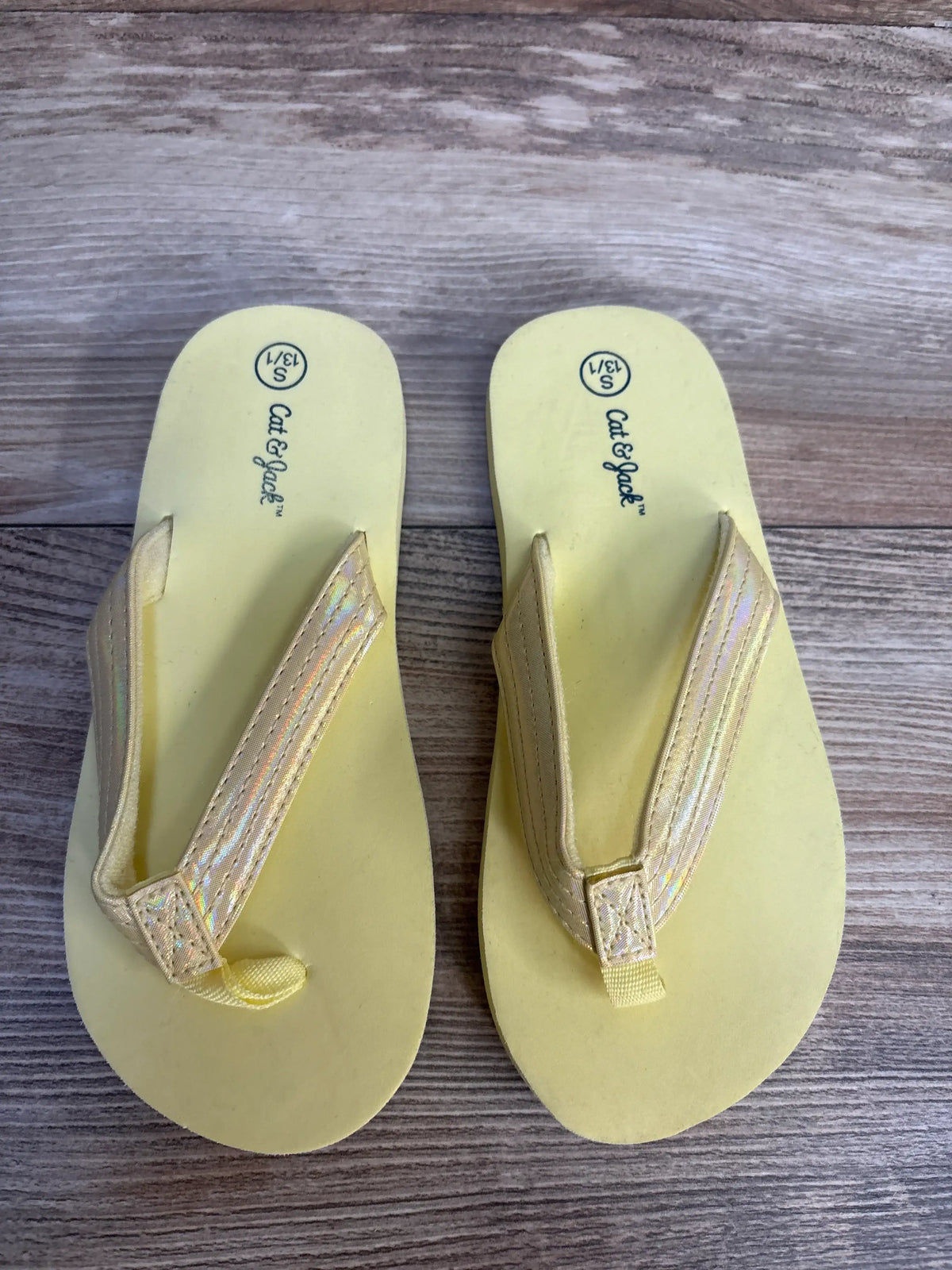 Yellow Cat & Jack kids flip flops with iridescent straps on wood background