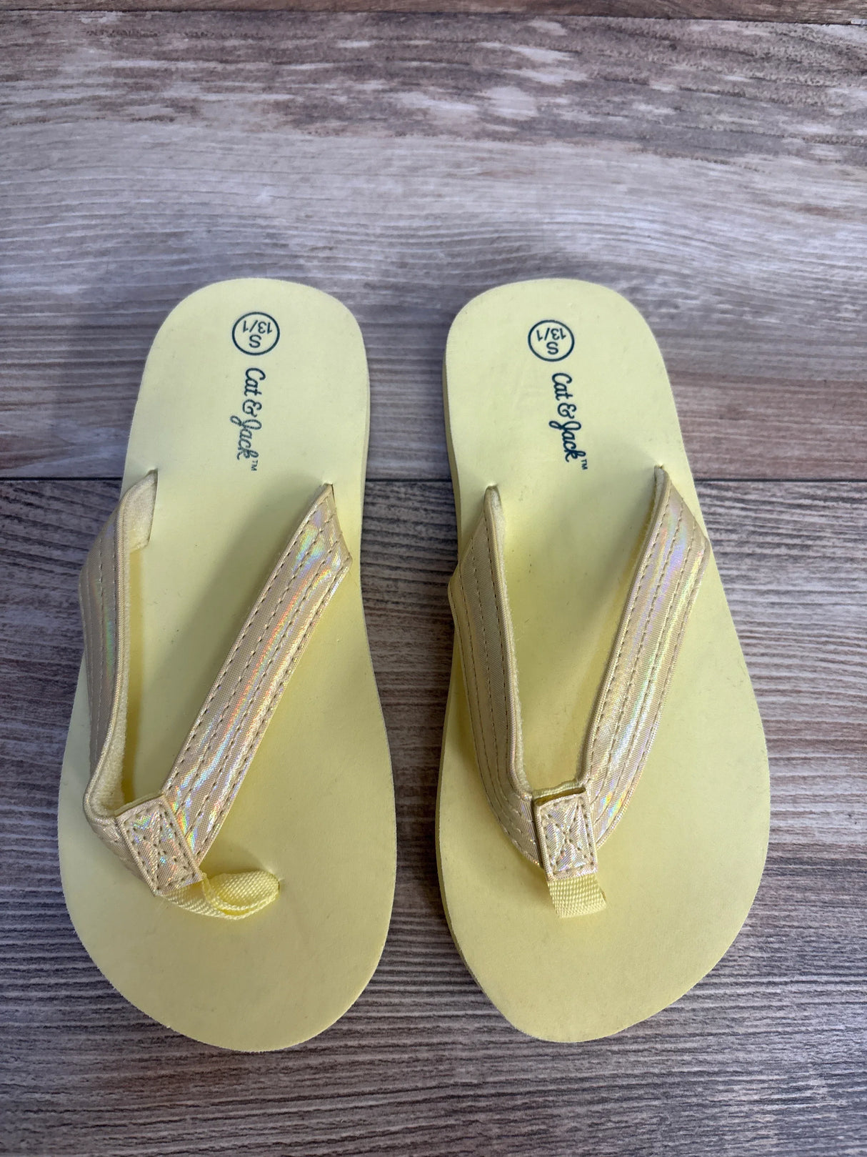 Yellow Cat & Jack kids flip flops with iridescent straps on wood background