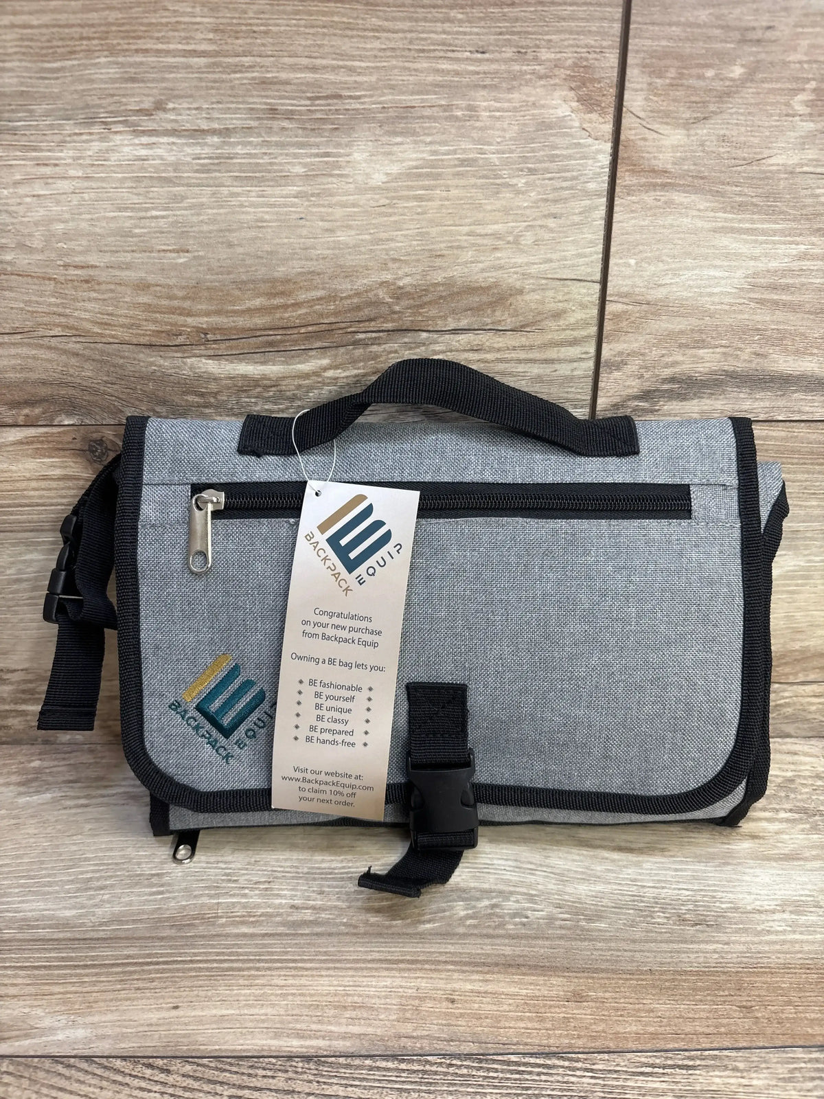 Front view of gray Backpack Equip portable changing station with top handle, stroller strap, D-ring and zippered pocket