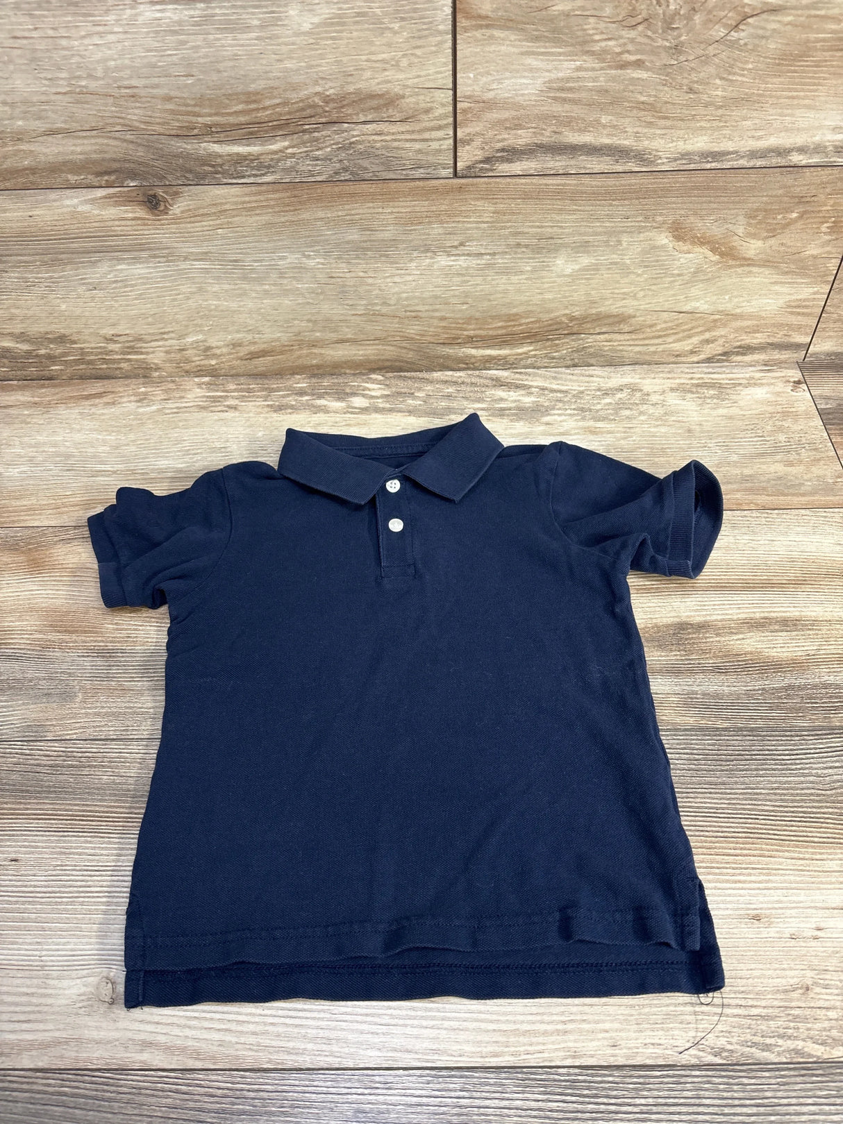 Navy blue short-sleeve polo shirt with collar and buttons on wooden floor