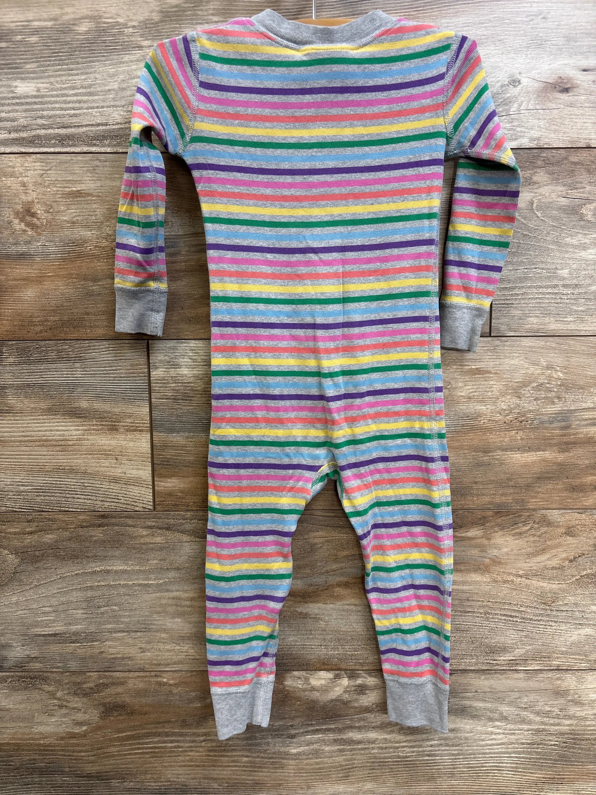 Front view of Hanna Andersson grey striped footless sleeper showcasing multicolor stripes and grey cuffs on a wood background
