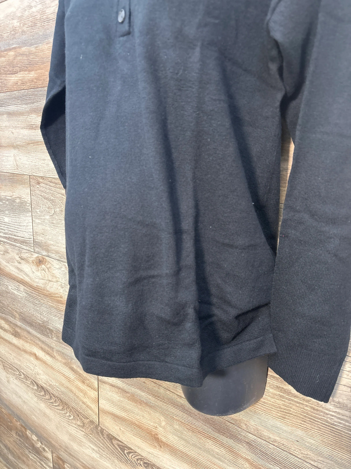 Black long sleeve polo shirt on mannequin with wooden background