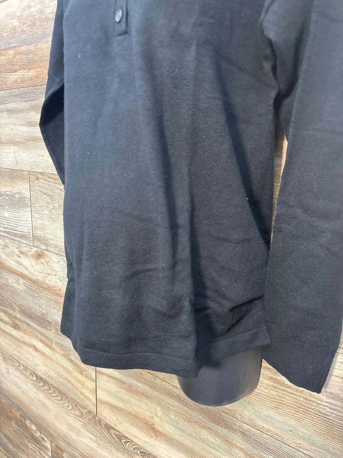 Black long sleeve polo shirt on mannequin with wooden background