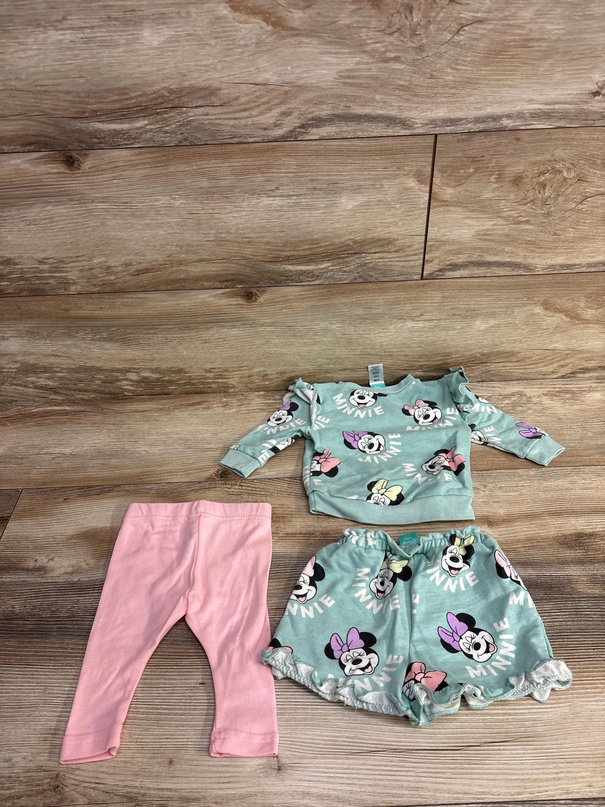 Toddler clothing set with mint green Minnie Mouse sweatshirt and shorts, plus solid pink leggings on wooden floor