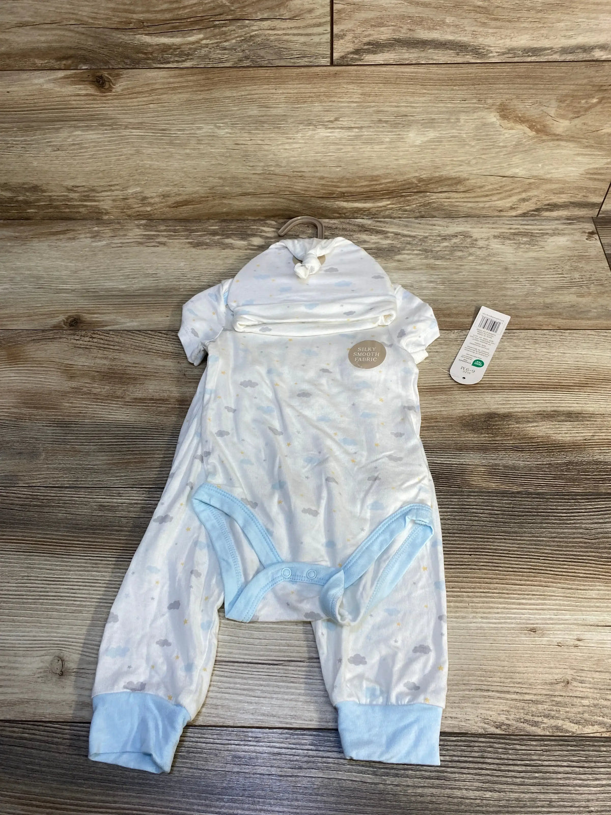 Light blue newborn sleeper and hat set with cloud print, silky smooth fabric, on wood floor