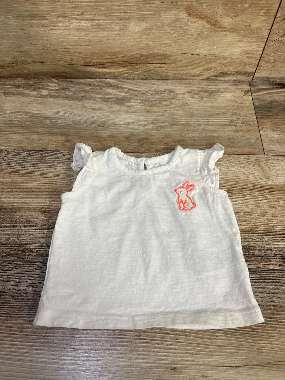Front view of Baby Gap embroidered rabbit shirt showcasing pink embroidered rabbit and ruffled sleeves on a wood floor