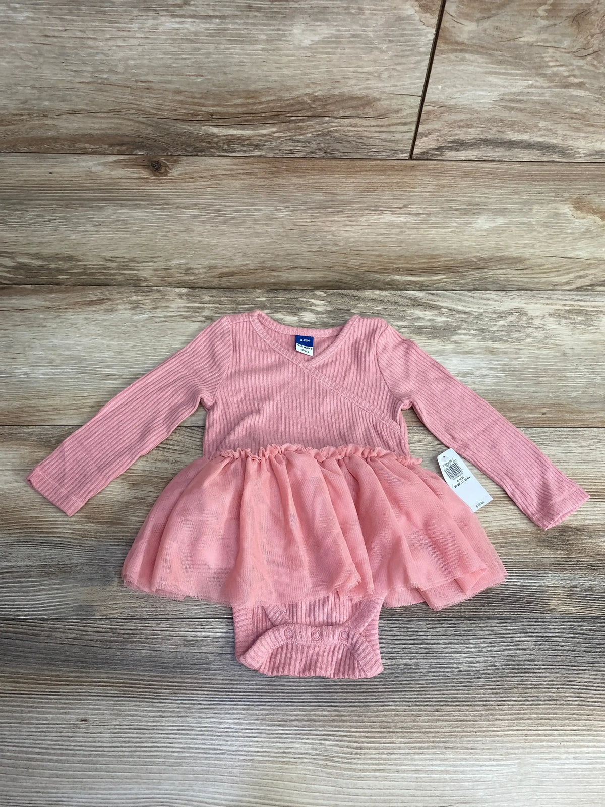 Pink long-sleeve ribbed baby bodysuit with tulle skirt, size 6-12 months, on wooden floor