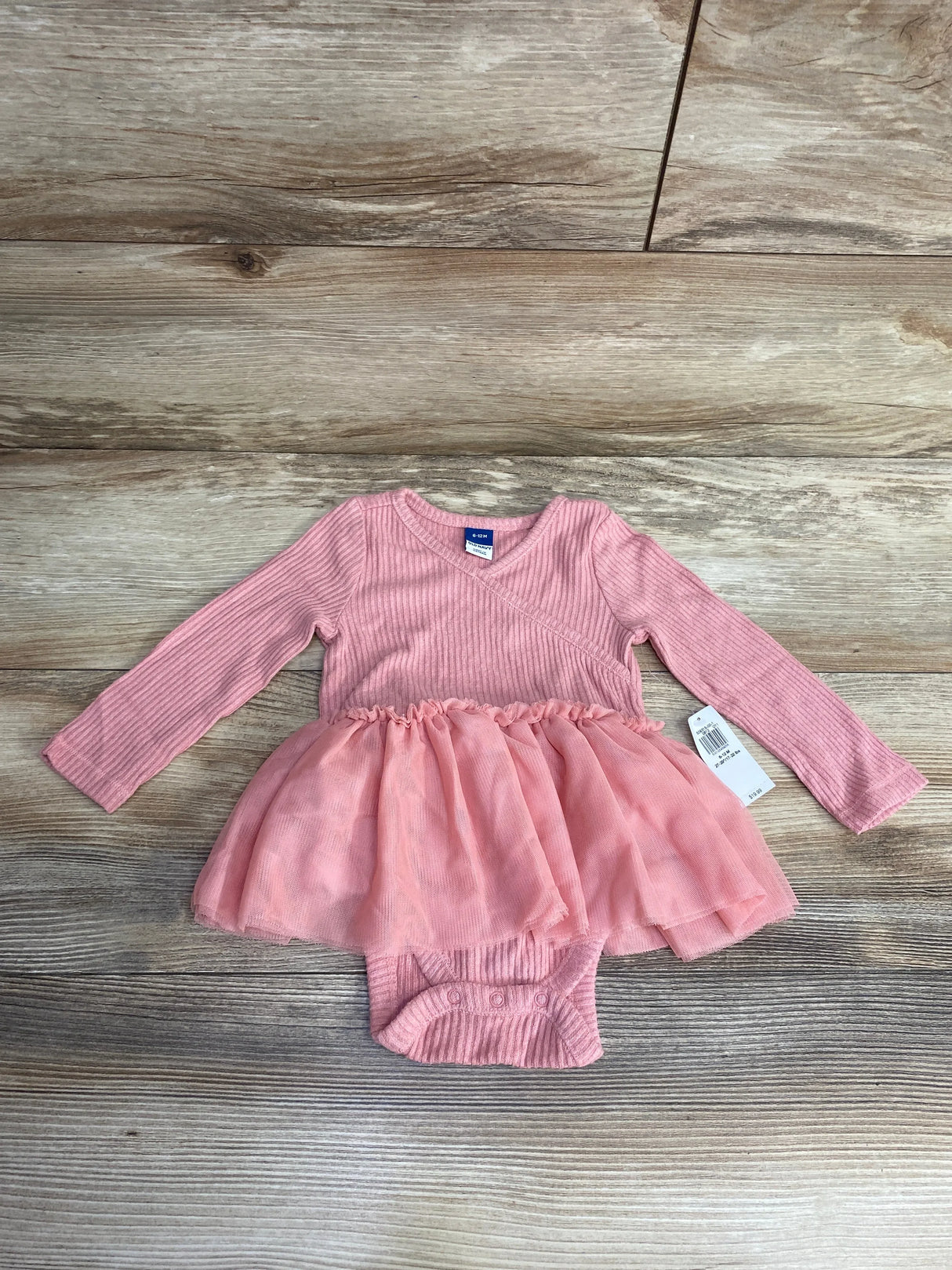 Pink long-sleeve ribbed baby bodysuit with tulle skirt, size 6-12 months, on wooden floor