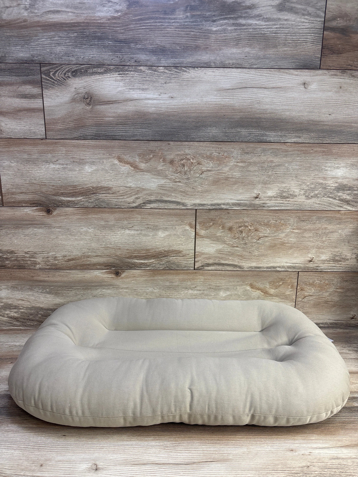 Beige rectangular pet bed on wooden floor and wall, minimalist dog or cat cushion