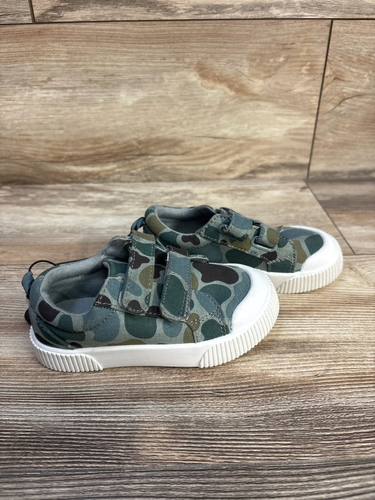 Side view of green Wonder Nation double-strap sneakers with white bump toes on a wood floor