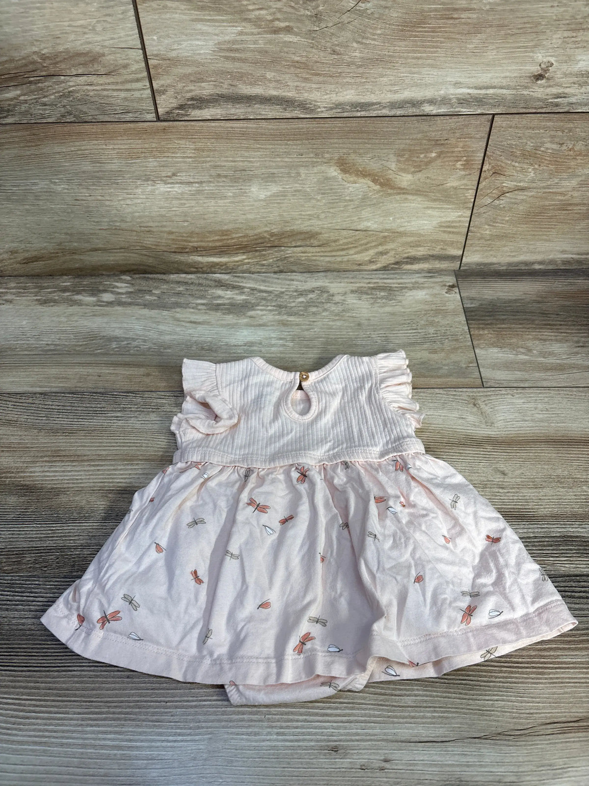 Front view of Carter’s pink bodysuit dress showing ruffled sleeves and A-line skirt on wood-look flooring