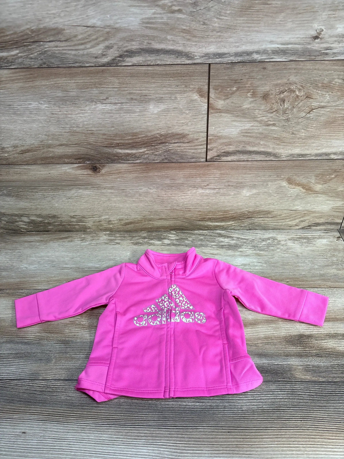 Pink Adidas toddler jacket with leopard print logo on wood background