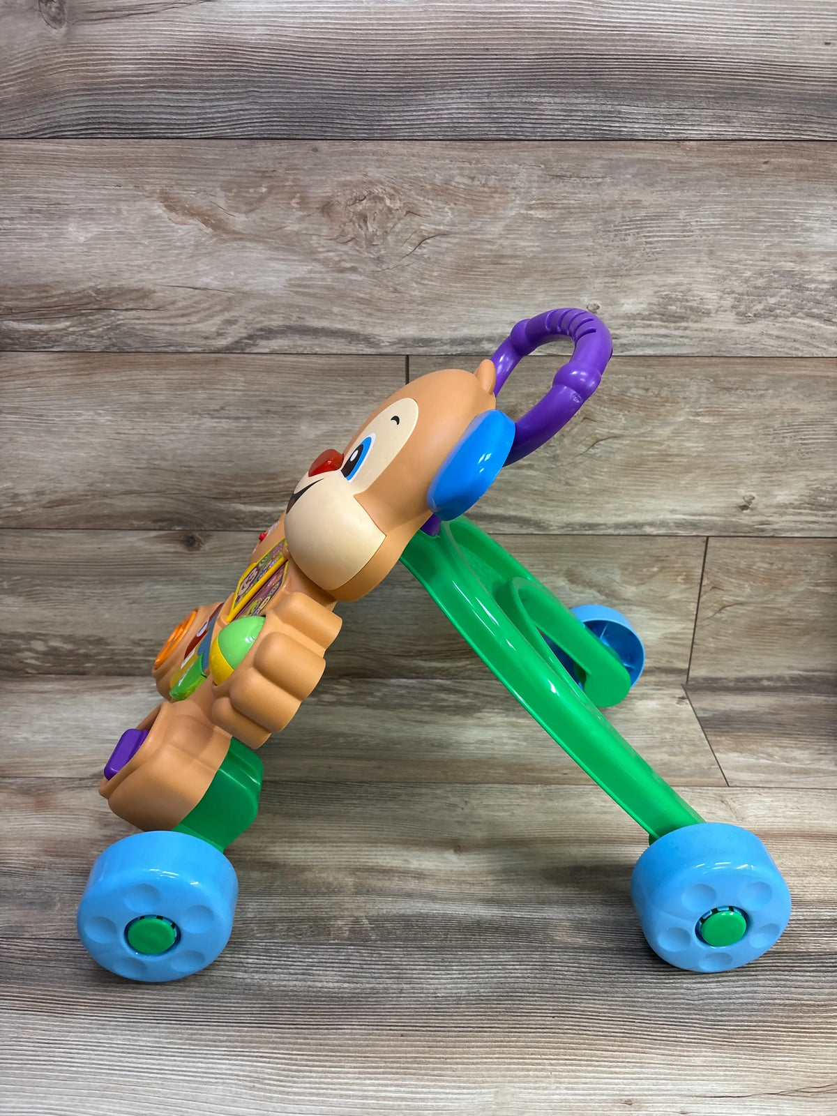 Side view of Fisher Price Laugh and Learn Smart Stages puppy walker showing purple handle and blue wheels on wood planks