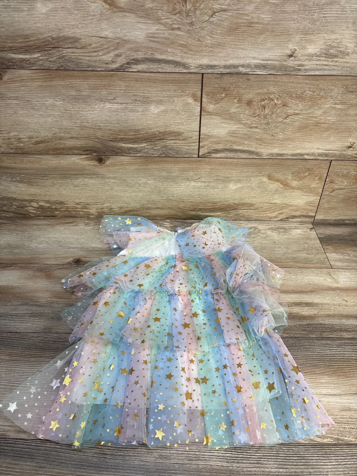 Front view of Star Print Layered Tulle Dress White sz 2T showcasing layered tulle and gold star print on wood background