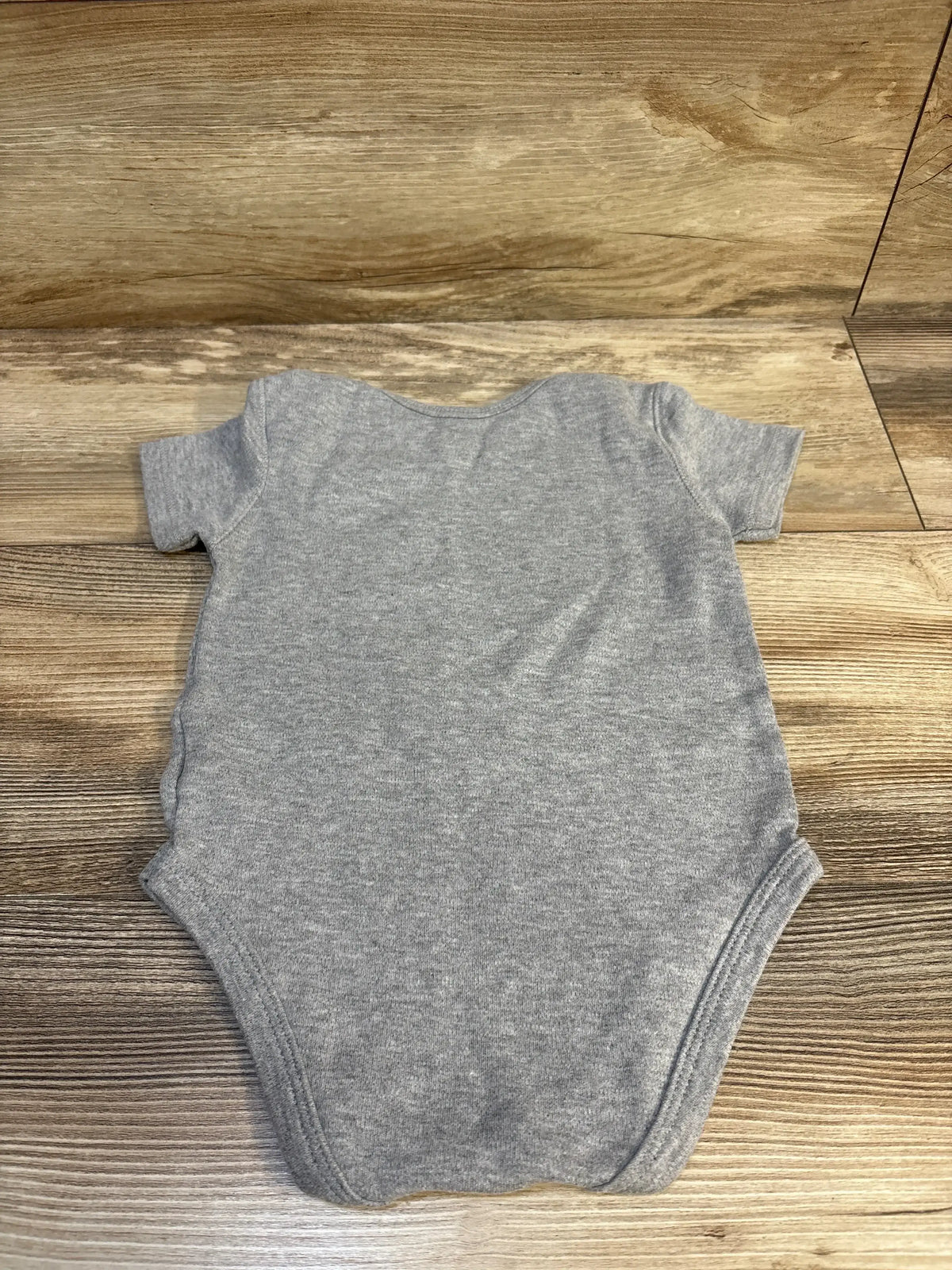 Gray short sleeve baby bodysuit laid flat on a wood surface