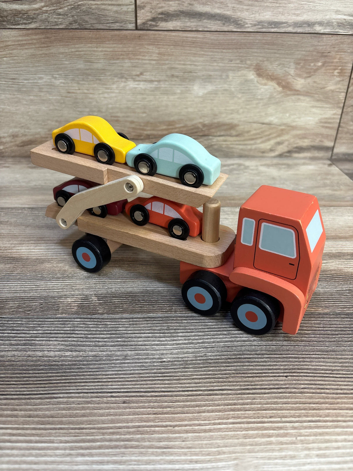Wooden toy car carrier truck with colorful mini cars on wood background