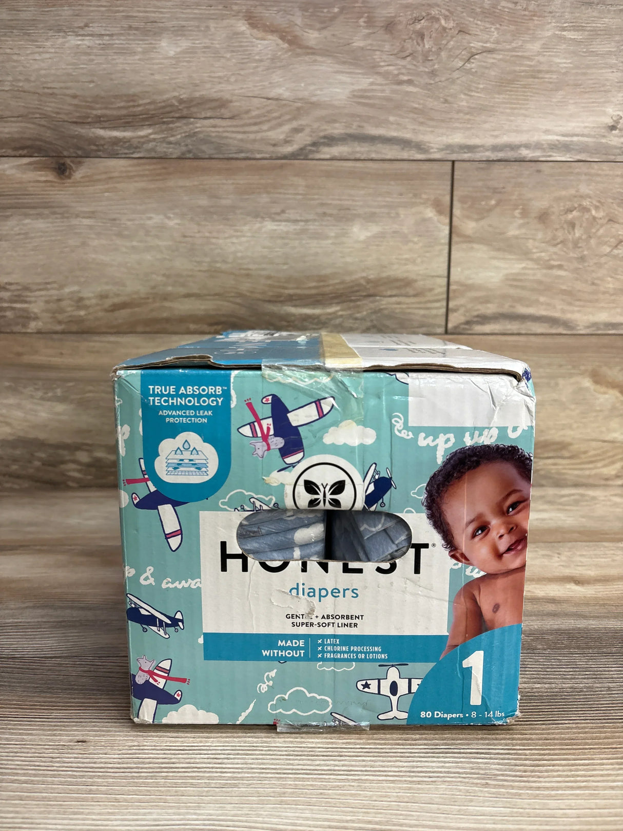 Box of Honest brand size 1 diapers for 8-14 lbs with airplane print and baby image