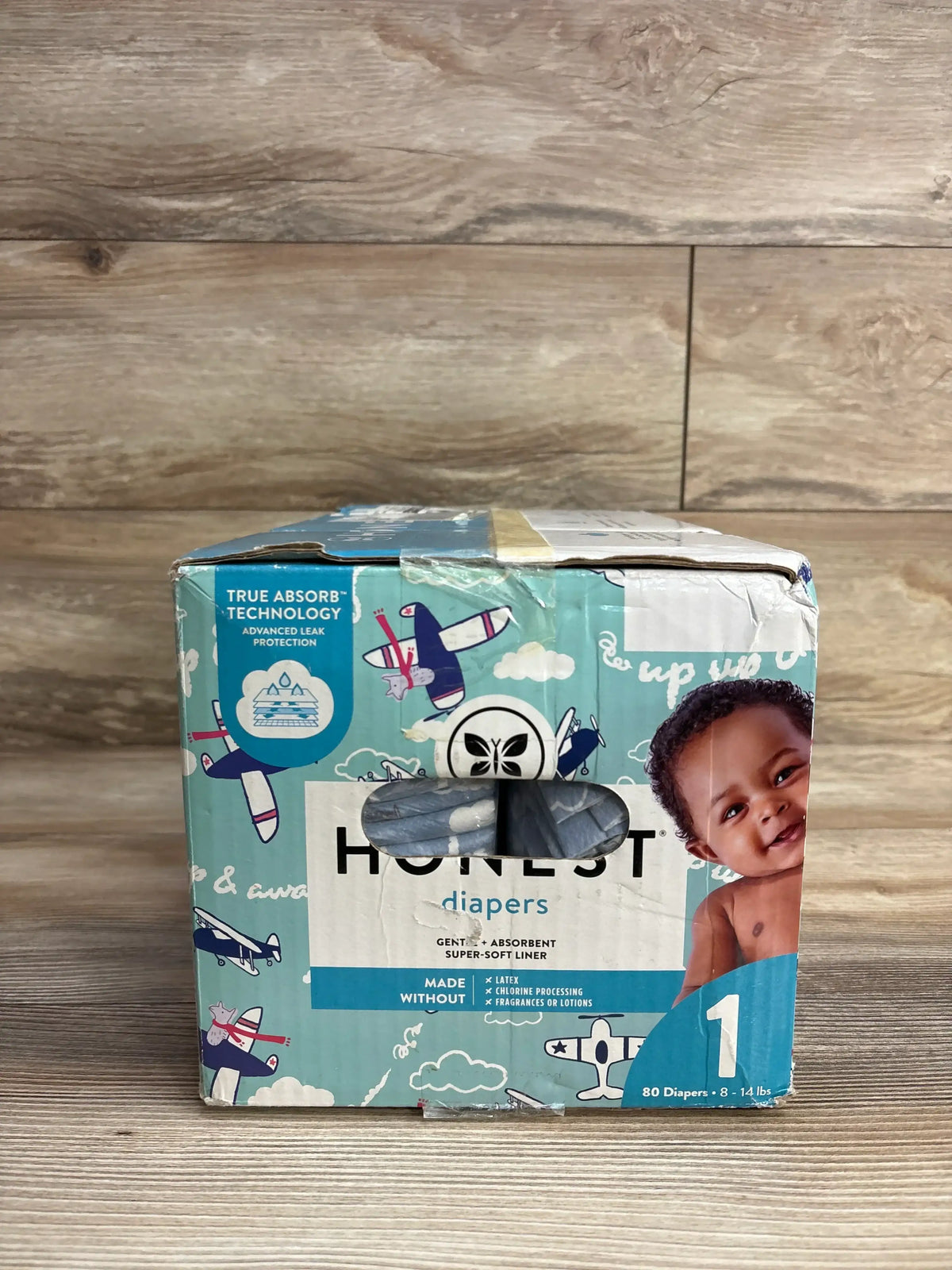Box of Honest brand size 1 diapers for 8-14 lbs with airplane print and baby image