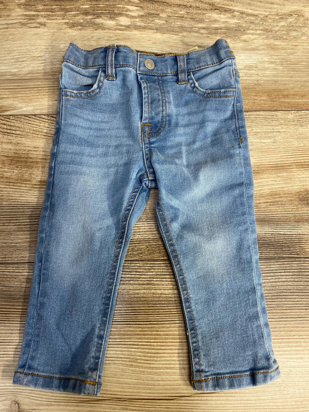 Light blue denim toddler jeans with classic five-pocket design on wooden floor