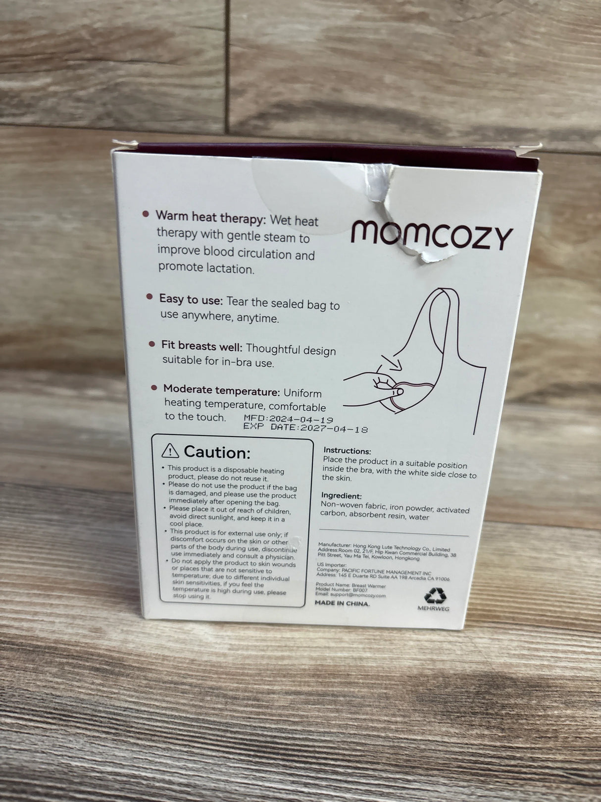 Rear view of Momcozy Instant Heat Breast Warmers 4-pack box showing product benefits and usage instructions on a wood surface