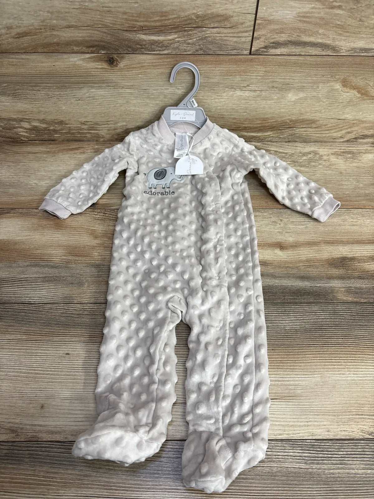 Soft beige baby onesie with textured dots and embroidered elephant, size 3-6 months, on wooden surface