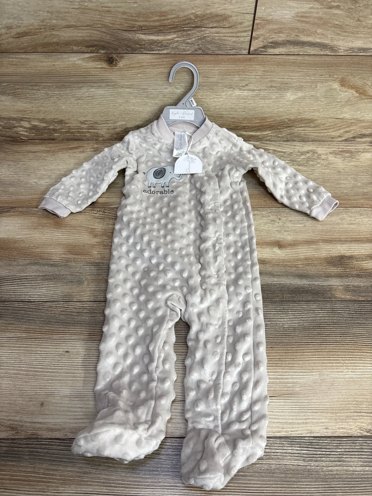 Soft beige baby onesie with textured dots and embroidered elephant, size 3-6 months, on wooden surface