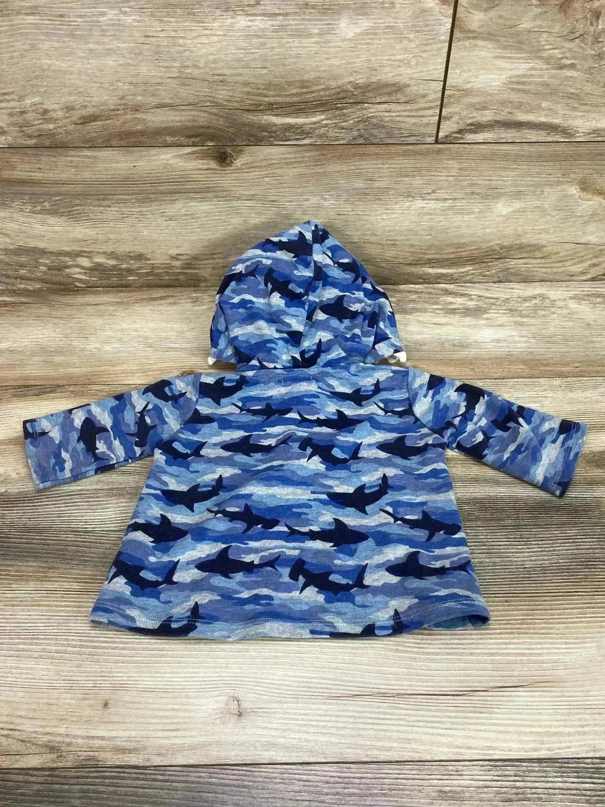 Back view of toddler shark-print hoodie showcasing attached hood and long sleeves on wood floor background