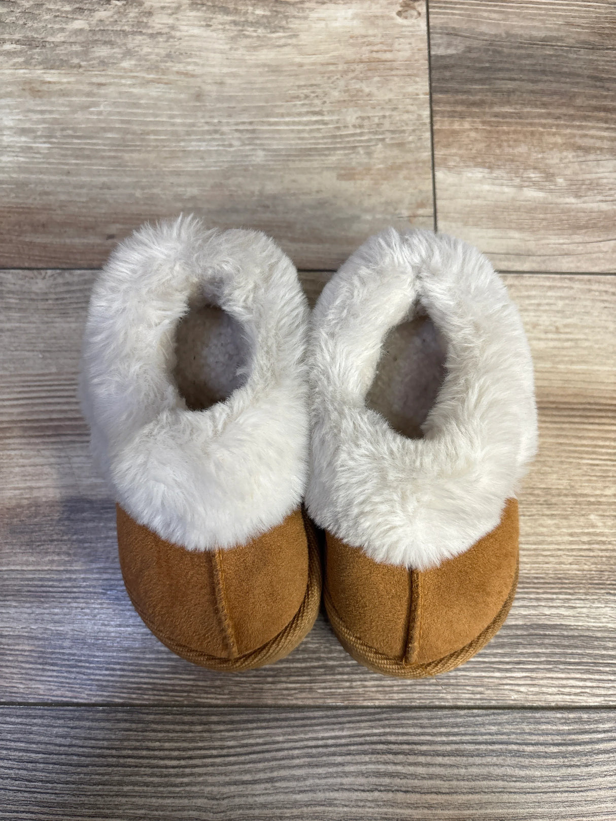 Top-down view of toddler brown faux-suede slippers with cream faux-fur trim, size 5C, on light wood background