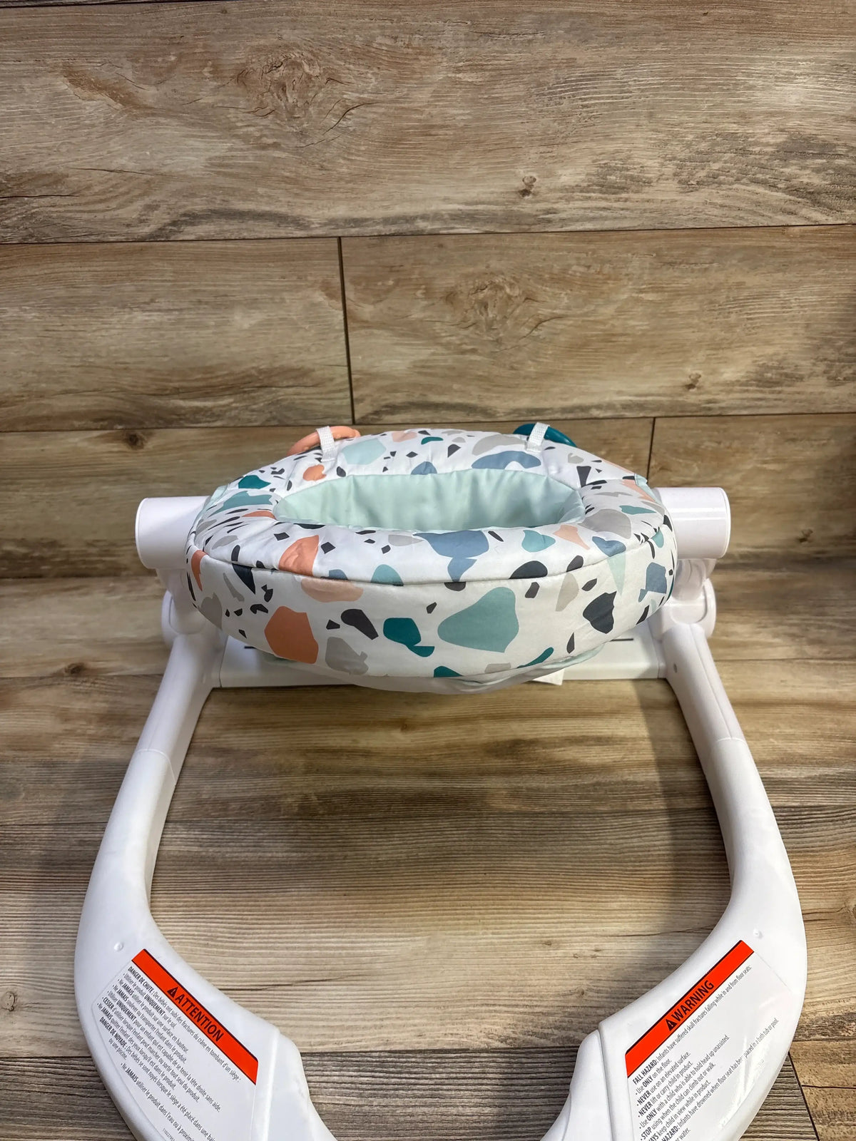 Front view of Fisher Price Sit-Me-Up Floor Seat in Pacific Pebble showcasing its patterned soft seat and wide white base on a wood floor