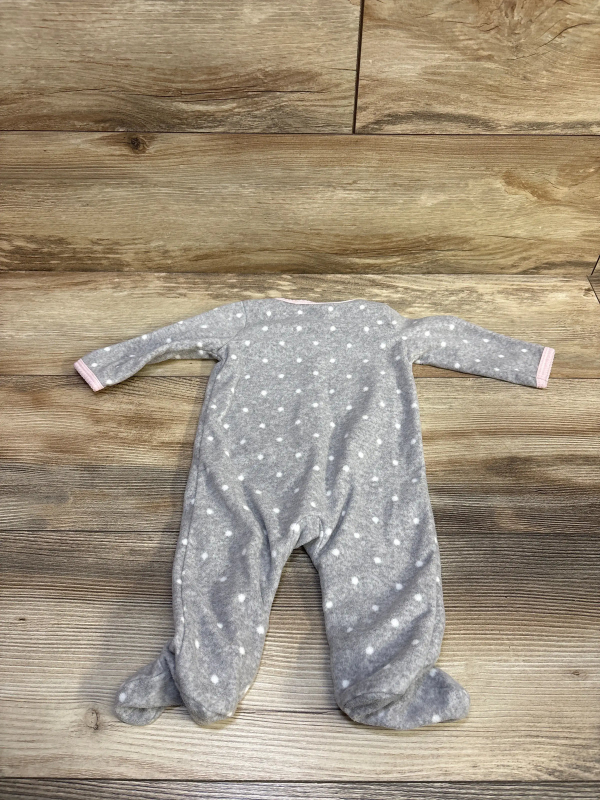 Grey Carter's blanket sleeper with white polka dots and pink trim on a wooden background