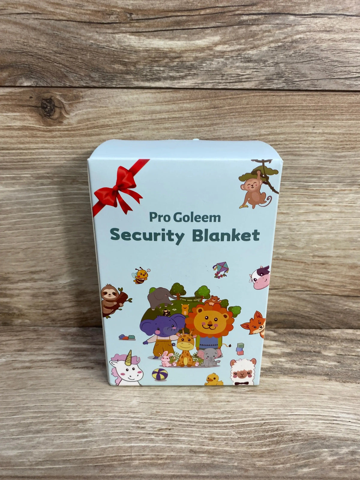 Front view of Pro Goleem bunny security blanket box with animal illustrations and red ribbon on wooden surface